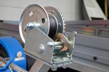 detailed photo of a small metal mechanical rope winch with a stainless steel hook