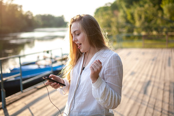 Beautiful girl listens to music at sunset