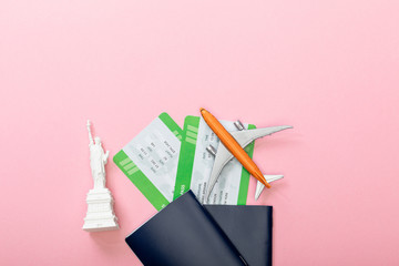 top view of air tickets near passports and small statue of liberty on pink