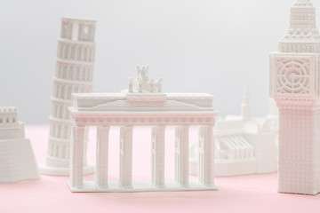 selective focus of brandenburg gate figurine near big ben tower statuette on grey and pink