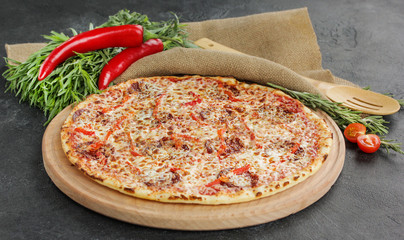 Italian concept, Italian cuisine. Pizza on a black background with fresh vegetables and herbs. Rustic.