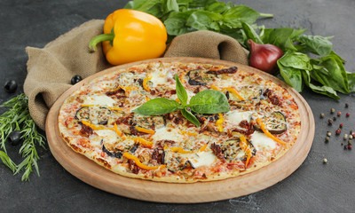 Italian concept, Italian cuisine. Pizza on a black background with fresh vegetables and herbs. Rustic.