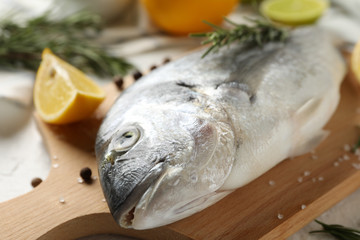 Cutting board with Dorado fish and cooking ingredients on white background, close up