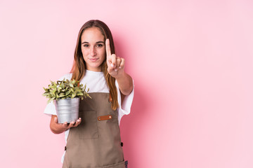 Young gardener caucasian woman isolated showing number one with finger.