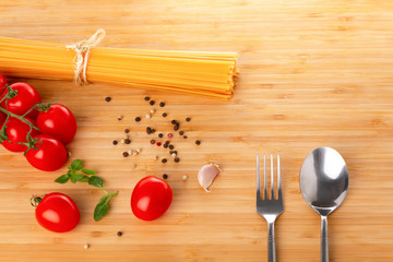 Spaghetti, raw tomatoes on a wooden table.