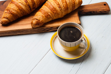 Croissants and coffee on a light background. The concept of delicious breakfast or lunch. At the bottom there is a place for copy space