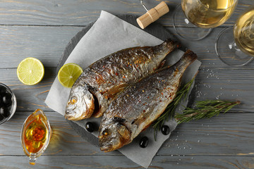 Baked Dorado on garnished wooden background, top view