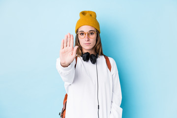 Young student woman isolated standing with outstretched hand showing stop sign, preventing you.