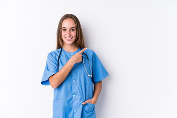 Young nurse woman isolated smiling and pointing aside, showing something at blank space.
