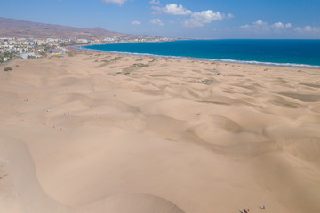 Scenic cinematic aerial view of Maspalomas sand dunes on seacoast on Gran Canaria island in Spain. Beautiful summer sunny look of white sand and sea of one of Canary islands.