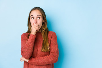 Young caucasian woman posing isolated  thoughtful looking to a copy space covering mouth with hand.