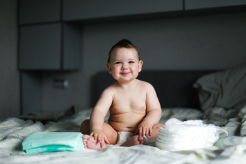 Cute chubby baby sitting with disposable diapers