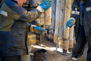 Offshore oil rig worker prepare tool and equipment for perforation oil and gas well at wellhead platform. Making up a drill pipe connection.Two roughnecks do the equipment for fixing of rig pipe
