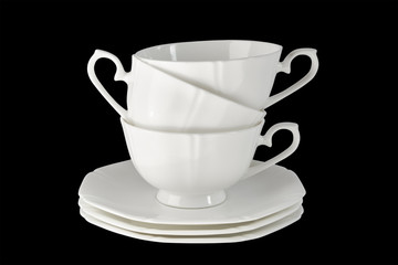White porcelain cup with a saucer for tea or coffee, demitasse or teacup. Isolated, black background.