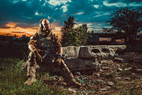 American soldier with the M4 rifle is having a rest. Sunset on the background.