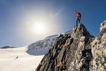 Foto op Canvas Climber or alpinist at the top of a mountain. A success of mountaineer reaching the summit. Outdoor adventure sports in winter alpine moutain landscape. Sunny day and a climber on a top of a peak. © Ondra