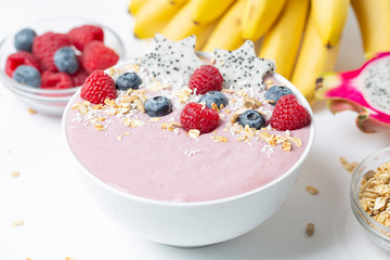 Healthy breakfast bowl: blueberry smoothie with raspberries, bananas, pitaya and granola. 