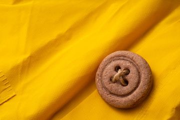 Cookies button with threads on a yellow cloak.