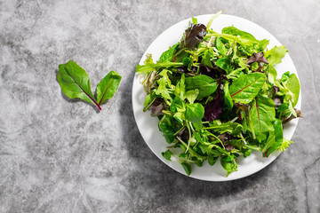 Green salad mix on dark stone background. Healthy eating concept.  Flat lay overhead with copy space for your design.