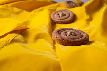Cookies button with threads on a yellow cloak. Arranged in a row.