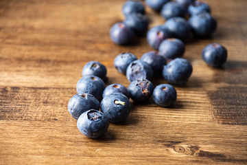 Top view of a group blue blueberries on dark wooden board with selective focus on horizontal and copy space
