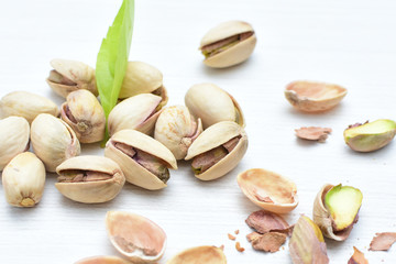  Pistachios on the white wooden background, accompanied by green leaf