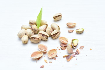  Pistachios on the white wooden background, accompanied by green leaf