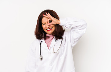 Middle age latin doctor woman isolated excited keeping ok gesture on eye.