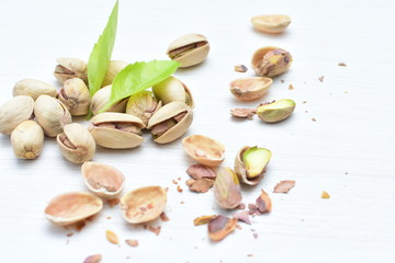  Pistachios on the white wooden background, accompanied by green leaf