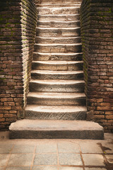 Ancient stone stairs with brick wall aside