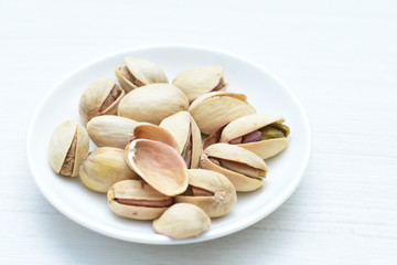  Pistachios on the white wooden background, accompanied by green leaf
