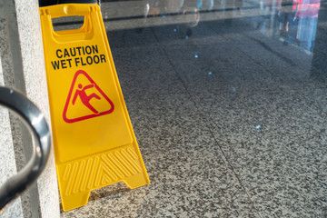 Wet floor sign in yellow color on the granite floor with copy space.