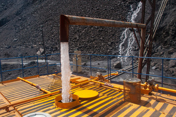 Filling water tank for irrigation machine.Heavy truck pours the road with water in the iron ore quarry. Dust removal, protection of the environment. Irrigation of the road from dust