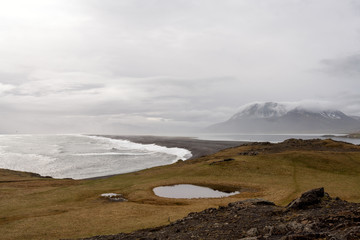 Hvalnes beach and volcano with snow and fog on Hvalnes peninsula on the south coast of Iceland. Traveling and landscapes concept.