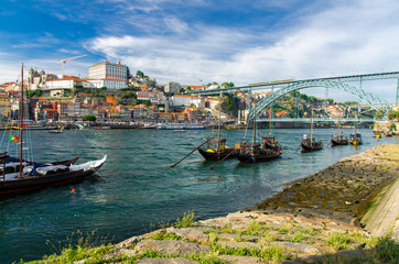 Fototapeta na wymiar Portugal, Porto, colored houses of old town in Porto, wooden boats on Douro river close up, Porto old town view, a group of boats sailing under a bridge, The Eiffel Bridge, Ponte Dom Luis