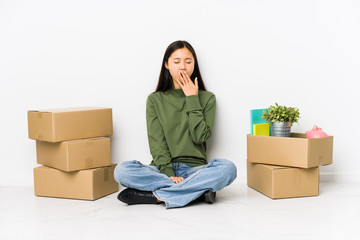 Young chinese woman moving to a new home yawning showing a tired gesture covering mouth with hand.