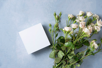  beautiful and delicate bouquet of white  roses lies on a blue background with white pure box present. Valentines day. Top view and copy space.
