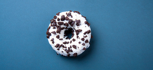 delicious fresh hearty black and white donut lies on a classic blue background. Jank food and high-calorie food