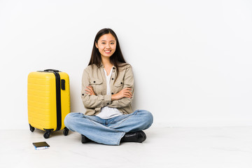 Young chinese traveler woman sitting holding a boarding passes who feels confident, crossing arms with determination.