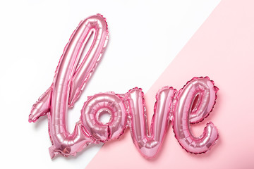 Pink balloons in the form of word Love on pink and white background. Valentines day celebration.