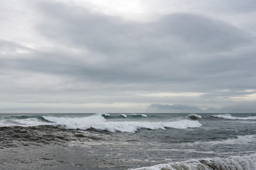 Waves crash ashore on Hvalnes beach on Hvalnes peninsula in southern Iceland. Traveling and photgraphy concept. Vestrahorn mountain chain in the background.