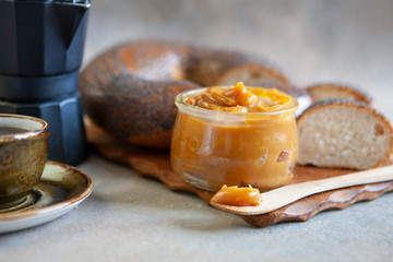 Glass jar of homemade salted caramel sauce with bread and walnuts. Close up