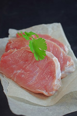 Raw meat with a sprig of green on a black background..Steak.