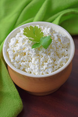 Fresh homemade cottage cheese in a clay plate on a wooden background.Healthy diet.