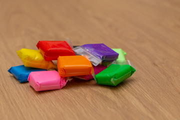 multi-colored plasticine sachets on a wooden surface
