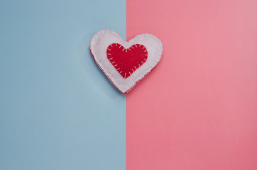 Handmade red and white heart on a pink and blue background with copy space. Background minimalism for Valentine's Day, Mother's Day, Birth of a child.