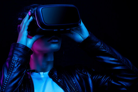 Young African American Girl Playing Game Using VR Glasses, Enjoying 360 Degree Virtual Reality Headset For Gaming, Isolated On Black Background In Neon Light