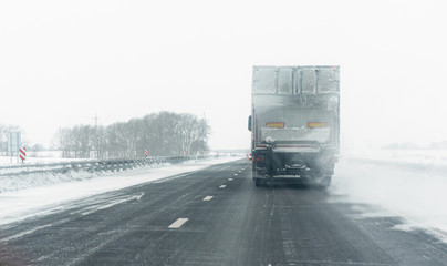 Truck on the winter snowy road background. Rear view.