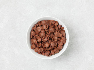 A bowl of chocolate flakes on a gray table.