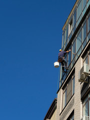 Fototapeta na wymiar Industrial climbing. Climber wash windows in a high-rise building. Cleaning of windows glass elements.